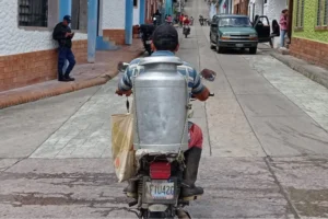 hombre con cantara de leche en una moto